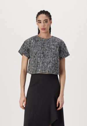 Svart och vit, kortärmad crop-top med en strukturerad, vävd mönster. Matchas med en svart omslagsskjorta.