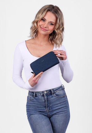 Tmavě modrá zipová peněženka vyrobená z texturované látky, s logem na přední straně a zápěstním popruhem pro snadné nošení.