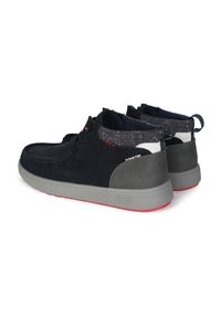 Scarpe in suede blu scuro con suola in gomma grigia, dotate di tacco grigio strutturato e dettagli rossi sulla suola e sulla cucitura.
