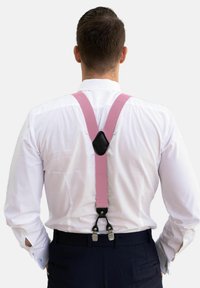 Rosa seler, fastgjort med en sort klemme, båret over en hvid skjorte, med en glat, flad tekstur og et Y-formet rygdesign.