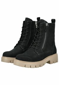 Stivaletti in suede neri con lacci alla caviglia, suole beige spesse e cerniere laterali, progettati per un abbigliamento casual o all'aperto.