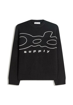 Svart tröja med vit grafisk design och texten "supply", ribbade muddar och fåll, gjord av ett mjukt stickat material.