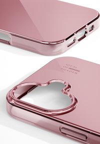 Transparante roze telefoonhoes met een glanzende afwerking, afgeronde randen en een hartvormige uitsparing voor de camera. "IDEAL OF SWEDEN" gegraveerd aan de zijkant.