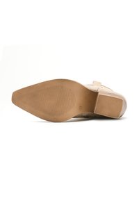 Zapato de ante beige con parte superior texturizada, puntera afilada y suela de goma marrón claro con patrones de estrías sutiles. Sin herrajes visibles.