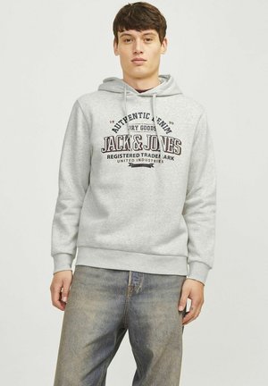 Gray hoodie with drawstrings, featuring black and burgundy printed logo text. Soft material, ribbed cuffs and hem, worn with blue jeans.