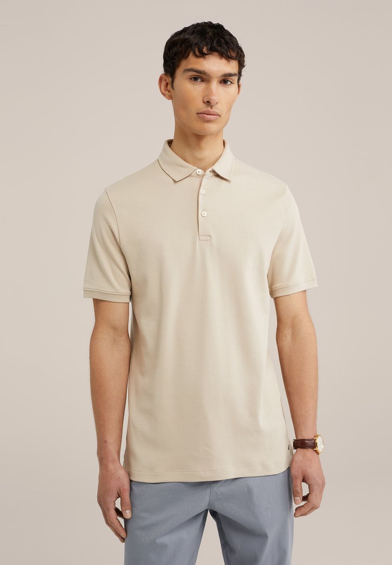 Bežna polo majica s klasičnim ovratnikom, tri dugmeta na prednjem dijelu, kratkim rukavima i mekom teksturom, u kombinaciji sa svijetloplavim hlačama.