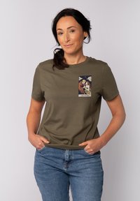 Olijfgroen katoen T-shirt met korte mouwen, met een geprinte afbeelding van twee figuren in tarotkaartstijl op de bovenste linkerborst.