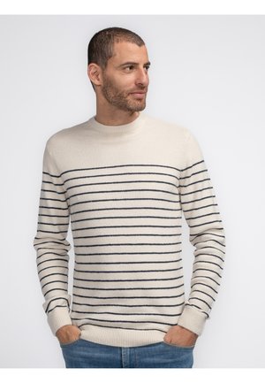 Cream-colored sweater with navy horizontal stripes, ribbed crew neck, and cuffs. Soft texture and fitted design, paired with blue jeans.