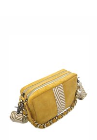 Sac bandoulière en daim jaune avec deux compartiments zippés, sangle tissée beige avec un motif en zigzag et accents en chaine dorée.