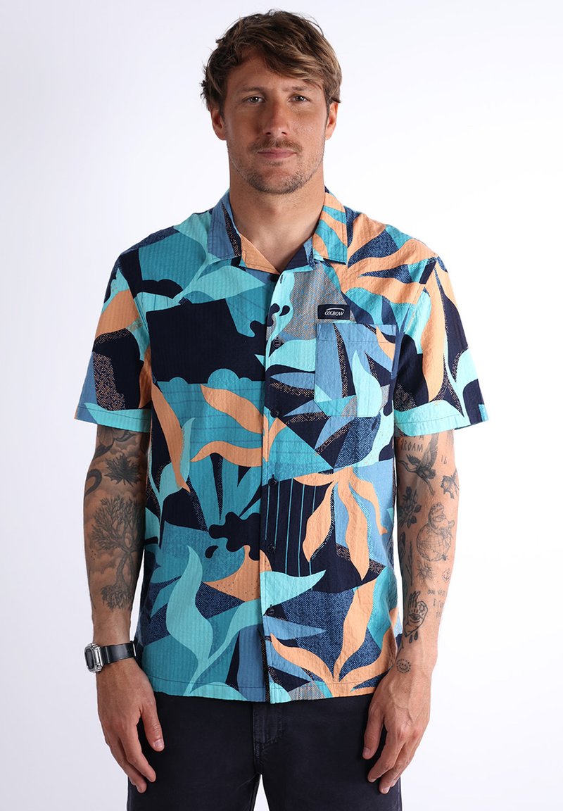 Chemise à manches courtes avec un motif de feuilles bleu vif, orange et noir ; fabriquée en tissu texturé ; dotée d'une poche poitrine.