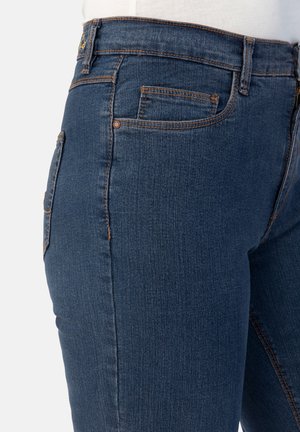Dunkelblaue Denim-Jeans mit eng anliegendem Schnitt, ausgestattet mit orangen Nähten, Taschen und einer glatten Textur. Die Seitenansicht hebt die Form und Designdetails hervor.