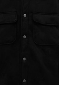 Veste noire vue de face avec deux poches à rabat et cinq boutons-pression en métal embossés du texte "PULL&BEAR."