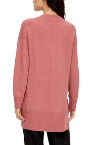 Długi rękaw, oversize'owy różowy sweter dzianinowy z prążkowanymi mankietami i dołem. Miękka tekstura, rozcięcia po bokach, bezszwowy design z tyłu.