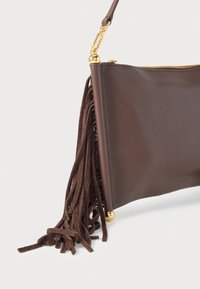 Barna bőrtáska arany színű fém díszítéssel, hosszú velúr rojtokkal, cipzáras záródással és sima, matt textúrával.