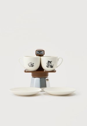 Két fehér kávéscsésze, rajzfilm egér és macska mintával, barna és ezüst színű espresso főzőn, alatta két fehér csészealjjal.