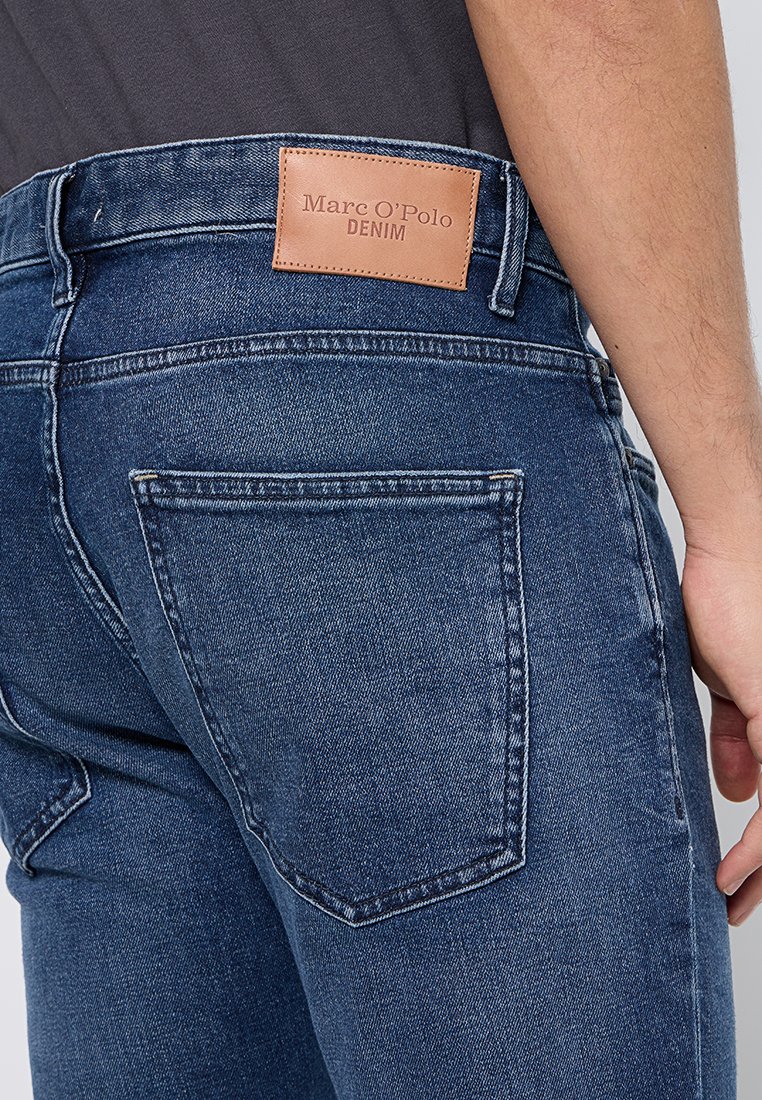 Dunkelblaue Jeans aus Denim mit einem Lederetikett, auf dem "Marc O'Polo DENIM" steht, mit standardmäßigen Gesäßtaschen und kontrastierenden Nähten.