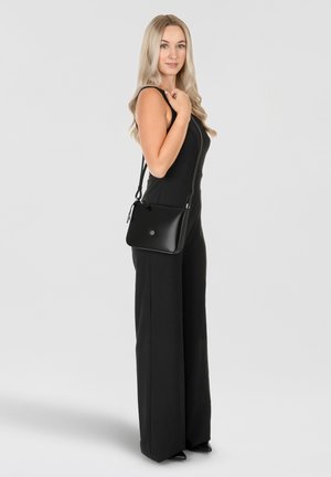 Schwarze Leder-Crossbody-Tasche mit rechteckiger Form, einfacher Gestaltung, verstellbarem Riemen und einem metallischen Logo-Detail auf der Vorderseite.