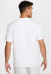 T-shirt blanc à manches courtes avec une coupe décontractée, en coton, présentant un col rond et une texture lisse, vu de dos.