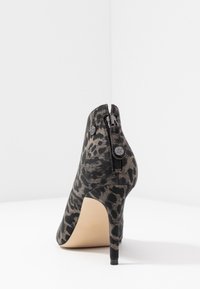 Bota de tacón alto con estampado de leopardo en negro y gris, punta puntiaguda, tejido texturizado, cierre lateral con cremallera y tacón de aguja delgado.