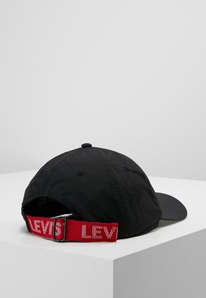 Sort baseballcap med justerbar rød rem med hvid tekst "LEVI'S", vist på en hvid overflade mod en ensfarvet baggrund.