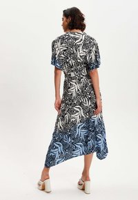 Floral patterned dress featuring a mix of black, white, and blue hues, with short sleeves and an asymmetric hemline, made from lightweight fabric.