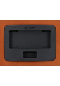 KLICKfix Halterung mit schwarzem Kunststoffgehäuse, rechteckiger Form und mittigem Schlitz, vor einer orangefarbenen strukturierten Oberfläche.