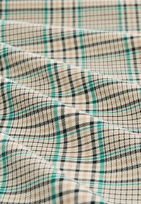Rutig tyg i beige, svart och gr�ön. Texturerad väv med diagonala linjer och rutor. Mjuk yta med en lätt glans.