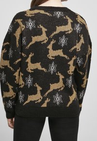 Czarny sweter dziany z wzorami złotych reniferów i białych płatków śniegu, o luźnym kroju i prążkowanych mankietach. Przytulna faktura.