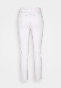 Jeans de tiro blanco con un diseño ajustado, que cuentan con cuatro bolsillos traseros, costura discreta y una cinturilla con una etiqueta. Textura suave.