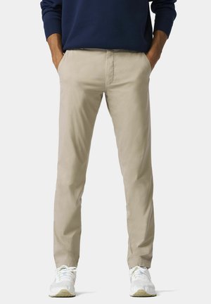 Beige Chinos aus Baumwolltwill, ausgestattet mit Seitentaschen, in geradem Schnitt und mit gesteppten Details, kombiniert mit weißen Sportschuhen.