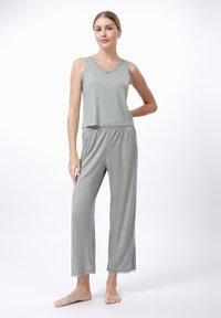 Szürke pamut loungewear szett, állítható nyakkivágású, ujjatlan topból és laza, elasztikus derekú nadrágból, amelynek alján csipkés díszítés található.