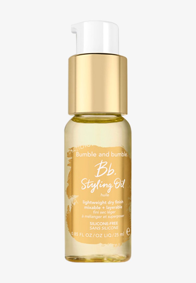 Bumble and bumble Bb. Styling Oil in una piccola bottiglia di vetro trasparente con un tappo dorato. Liquido giallo all'interno, etichettato con testo bianco.