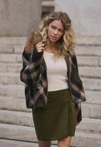 Gyapjú keverék dzseki prém díszítéssel, fekete, tejszínszínű és rózsaszín kockás mintázattal. Illeszkedő olívazöld szoknyával párosítva.