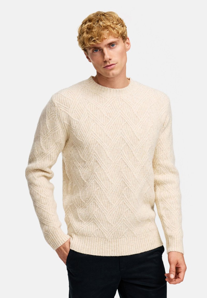 Sweter w kremowym kolorze z teksturowanej dzianiny, z wzorem w zygzak, prążkowanym dekoltem i mankietami, o luźnym kroju.