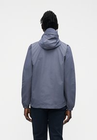 Navy blue hooded jacket made from lightweight material, featuring a simple design with elastic cuffs and a straight cut.