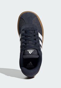 Navy blue textile sneaker with white stripes and a rubber gum sole. Features round laces, a padded collar, and branding on the tongue.