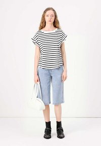 Black and white striped short-sleeve top with a crew neckline, paired with light blue denim culottes, black ankle boots, and a white handbag.