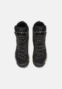 Black high-top hiking boots with textured fabric, reinforced toe, and braided laces. Features sturdy rubber soles and contrasting accents.