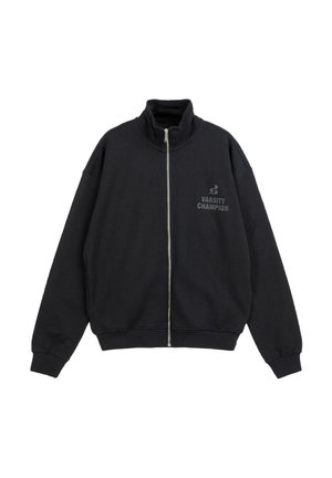 Czarna kurtka zapinana na suwak z wysokim kołnierzem, długimi rękawami i napisem „Varsity Champion” na lewej stronie klatki piersiowej.