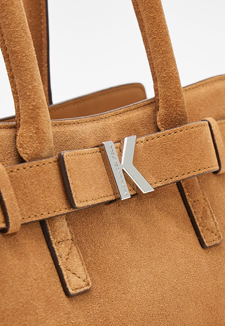 Bolso de ante color tostado con doble asa y cierre con el logo "K" en plata en la correa frontal.