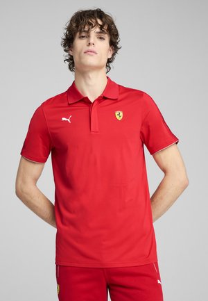 Rød polo-shirt med korte ærmer, hvid kant og broderet Ferrari-logo på brystet. Lavet af glat, let stof.