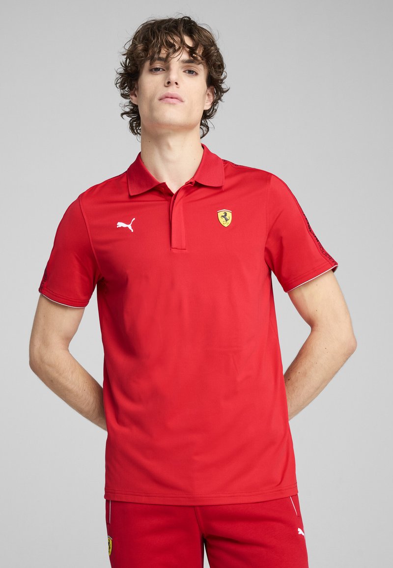 Rød polo-shirt med korte ærmer, hvid kant og broderet Ferrari-logo på brystet. Lavet af glat, let stof.