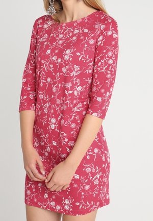 Červené květované šaty s tříčtvrtečními rukávy, zdobené bílým květinovým vzorem a kulatým výstřihem. Měkká tkanina a přiléhavý střih.
