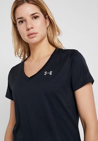 Navyblaues kurzärmliges V-Ausschnitt-Shirt aus leichtem Stoff, mit einem kleinen silbernen Under Armour-Logo auf der linken Brustseite.