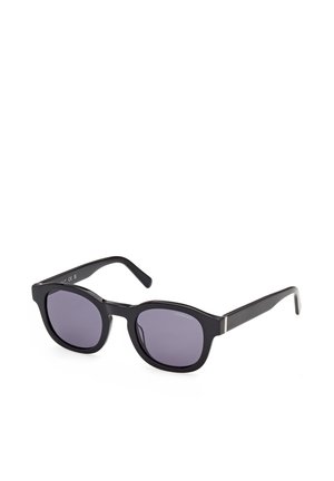Lunettes de soleil rectangulaires noires avec verres teintés foncés et branches fines, présentées sur fond blanc.