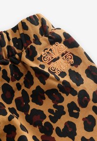 Leoparda raksta audums ar oranžām un melnām plankumiem uz smilškrāsas fona. Arī ir izšūta oranža tauriņa detaļa. Mīksta tekstūra.