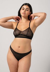 Soutien-gorge noir transparent et culottes assorties avec des bretelles fines, une texture douce et un tissu transparent. Le design est minimaliste et sans couture.