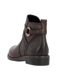 Bottine en cuir marron avec une pointe arrondie, des brides décoratives, des accents métalliques et un détail texturé sur le talon. Semelle en caoutchouc.
