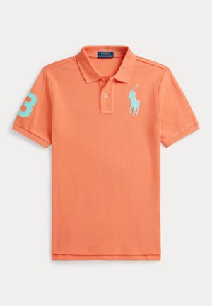 Koszulka polo w kolorze koralowej pomarańczy, z dwuklawiszową listwą, krótkimi rękawami, niebieskim haftowanym logo oraz numerem „3” na lewym rękawie.