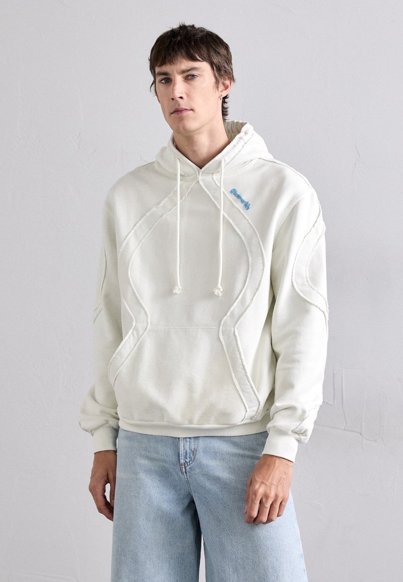Sudadera blanca hecha de una tela suave con un diseño bordado y un bolsillo tipo canguro. Cuenta con una capucha ajustable y bordado en azul claro.